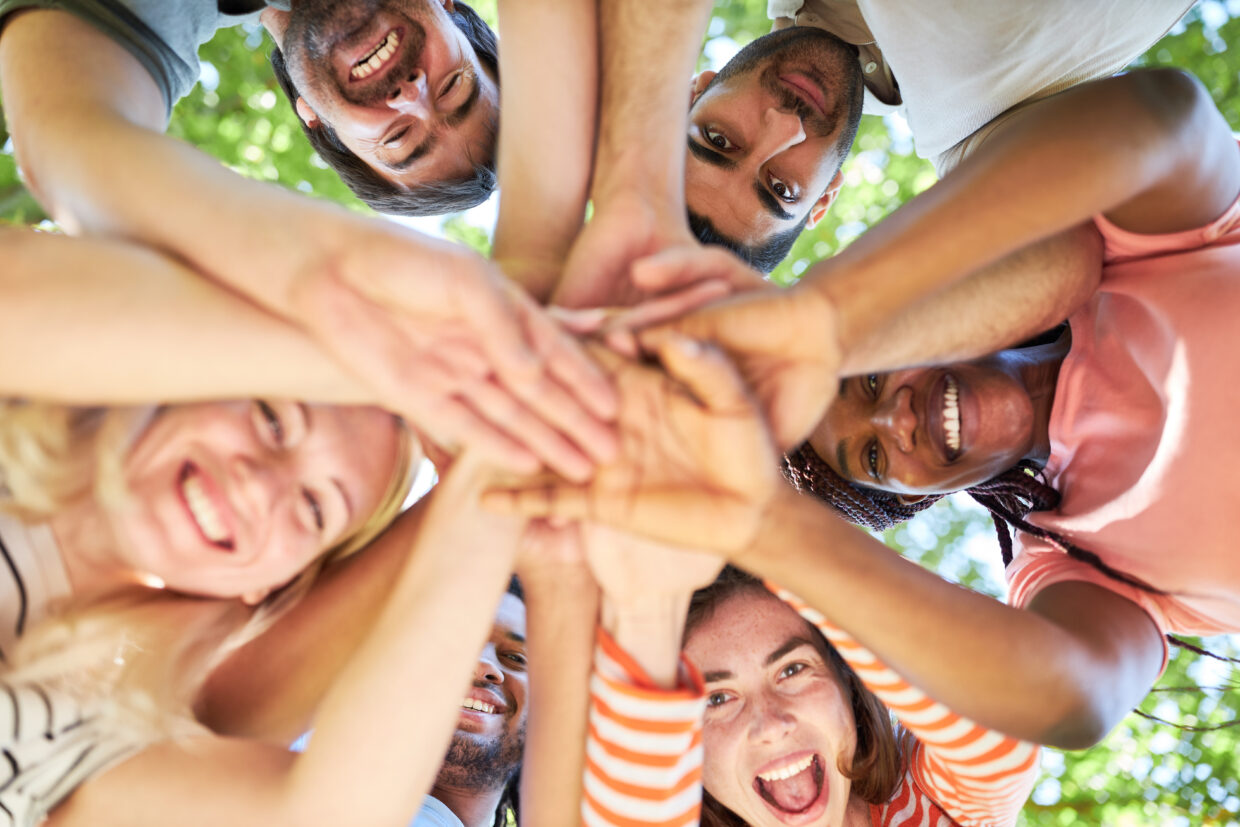 Group of happy young people while stacking hands