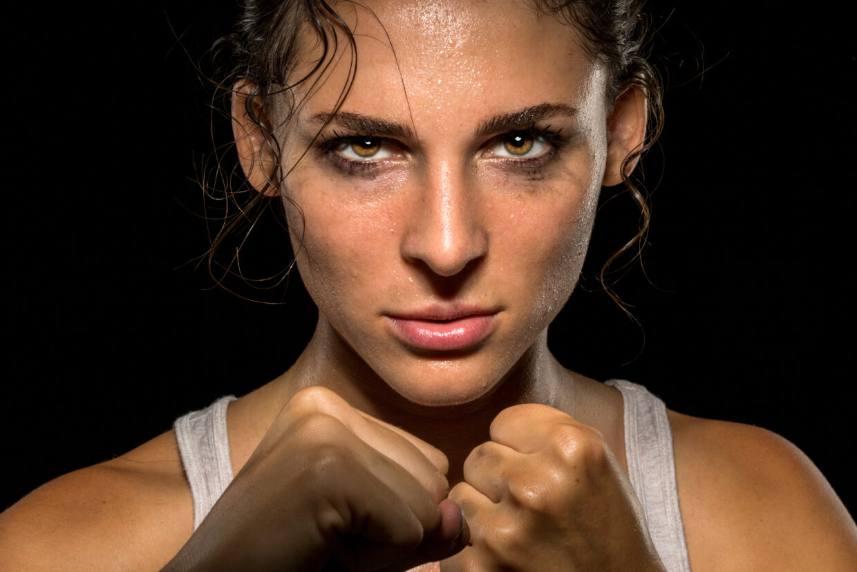 Intense female fighter stare with fist up in self defense traini